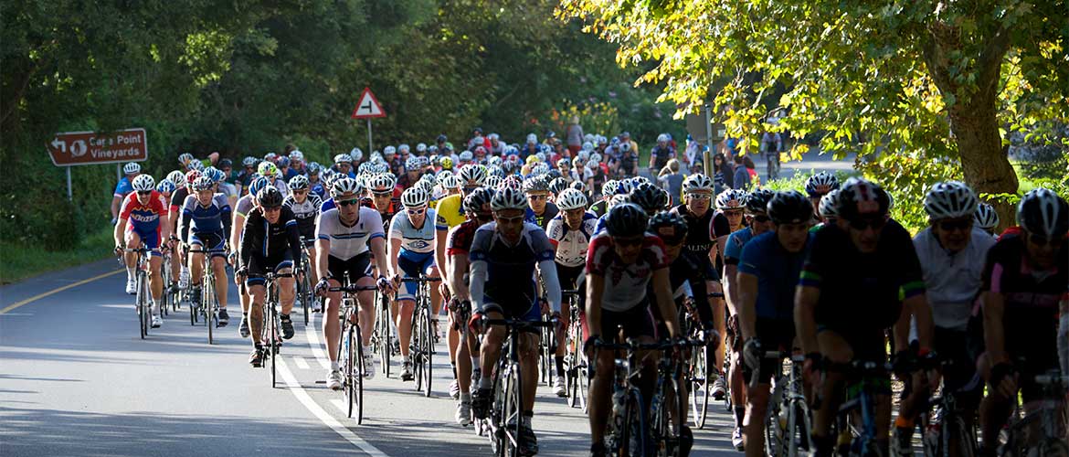 Cyclists from the Cape Argus Cycle Tour pass through the green village of Noordhoek in Cape Town, South Africa.